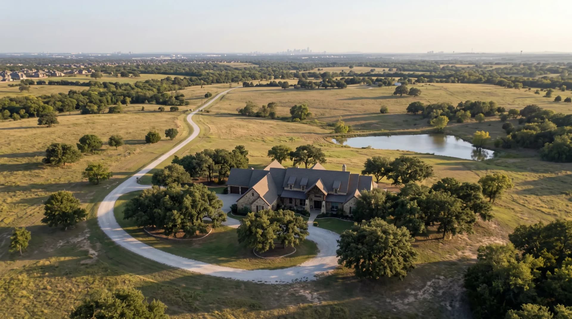Aerial view of a North Texas estate on rolling acreage with live oaks and a pond, illustrating how land drives luxury home prices in Dallas–Fort Worth.